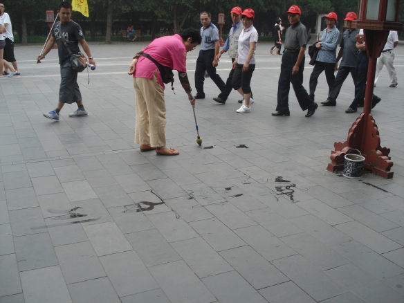 The woman painting on the pavement with water.